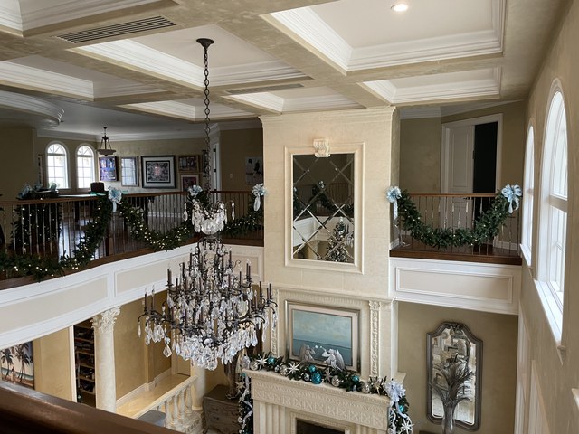 A two story foyer with garland along the balcony rail and a crystal chandelier
