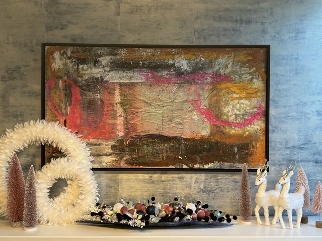 A credenza with a white wreath, blush trees and two glass deer
