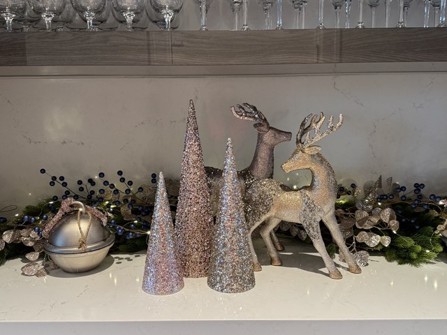 A mantel with glitter cones, a mercury sphere and two standing deer