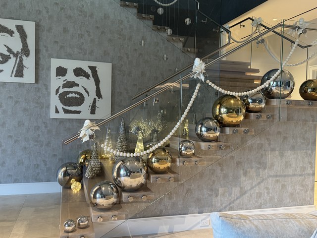 Mercury glass spheres and a beaded garland along a glass stair rail