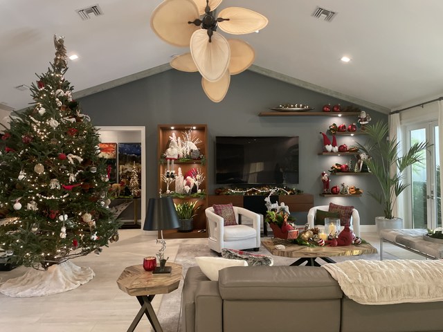 A vaulted living room with a red and white tree beside the shelving