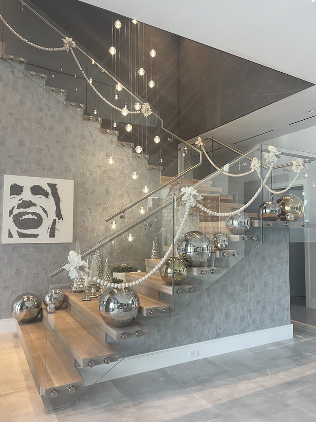 The staircase garland seen from the entry, with lit strands overhead
