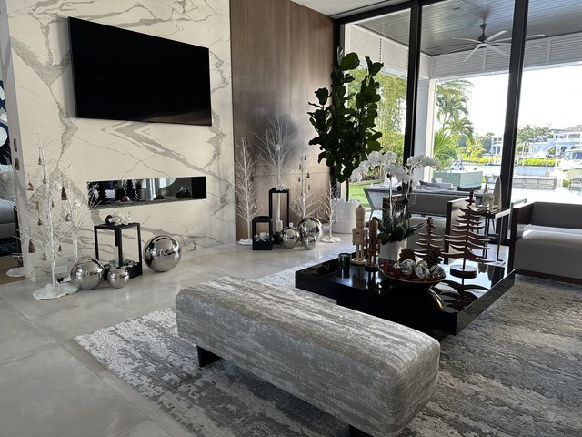 A living room with silver trees and spheres on the marble fireplace wall