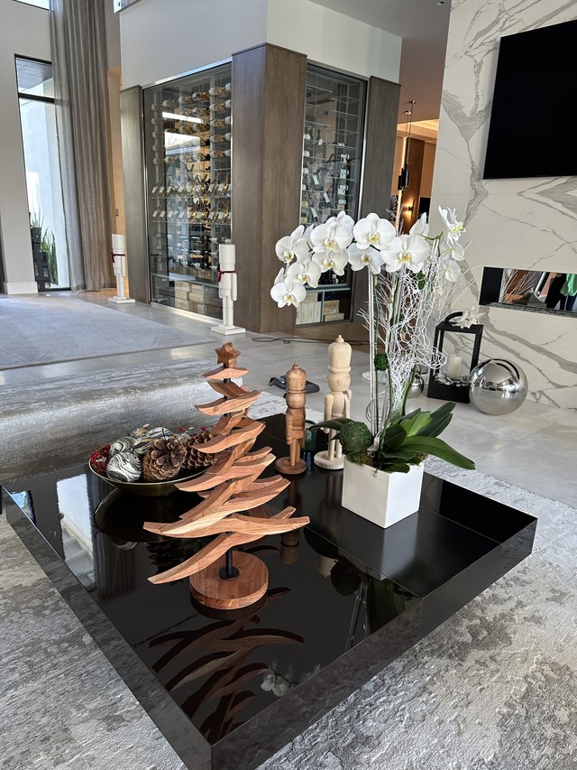 A coffee table with a wooden spiral tree, orchids and mercury glass