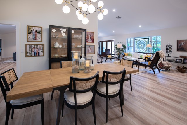 A dining room with a wood table, black cane chairs and a globe chandelier