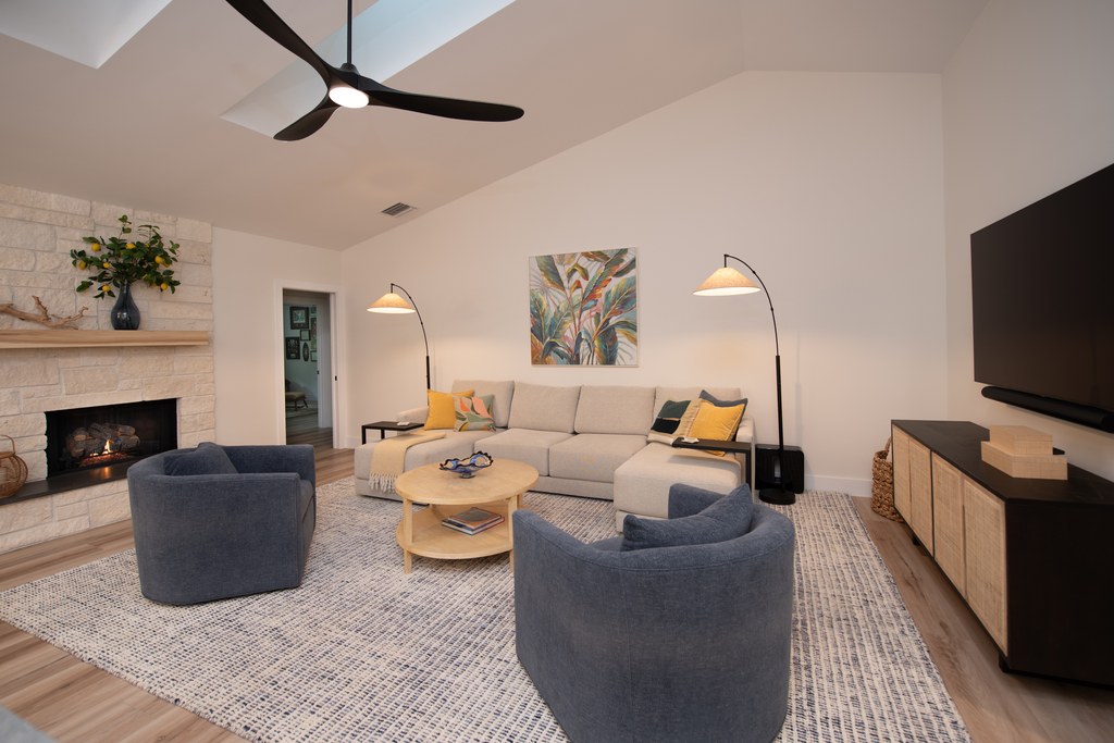 A family room opening to the kitchen, with layered seating and a stone fireplace