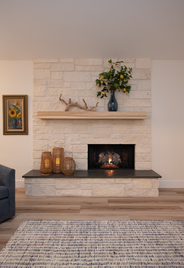 A stacked stone fireplace with a timber mantel and a driftwood arrangement